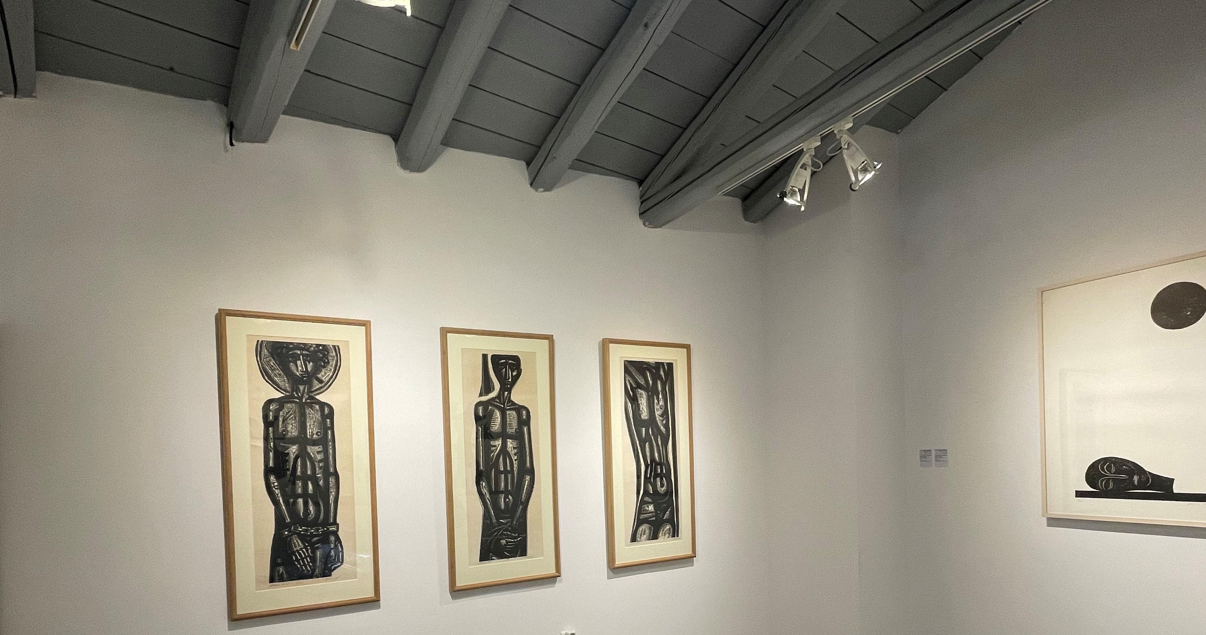 The works Slave 1, Slave 2 and Slave 3 hanging on a white wall. Another piece on the side. The pieces at the exhibition area