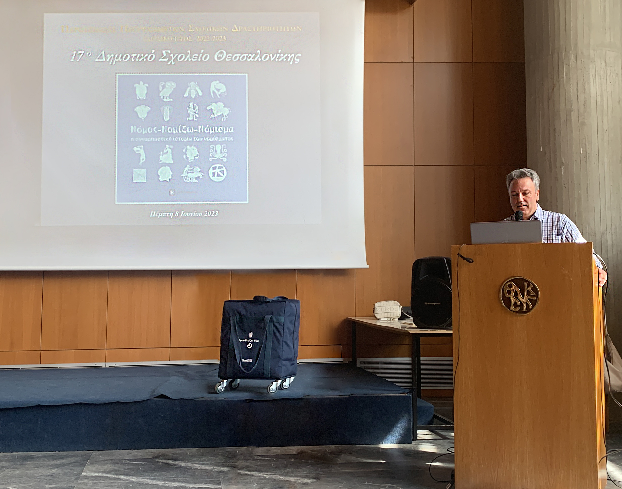 Ο Διευθυντής του 17ου Δημοτικού Σχολείου Θεσσαλονίκης, κ. Δημήτρης Τσιντάρης, στο βήμα και αριστερά βιντεοπροβολή.  Στιγμιότυπο από την εκδήλωση στη Θεσσαλονίκη