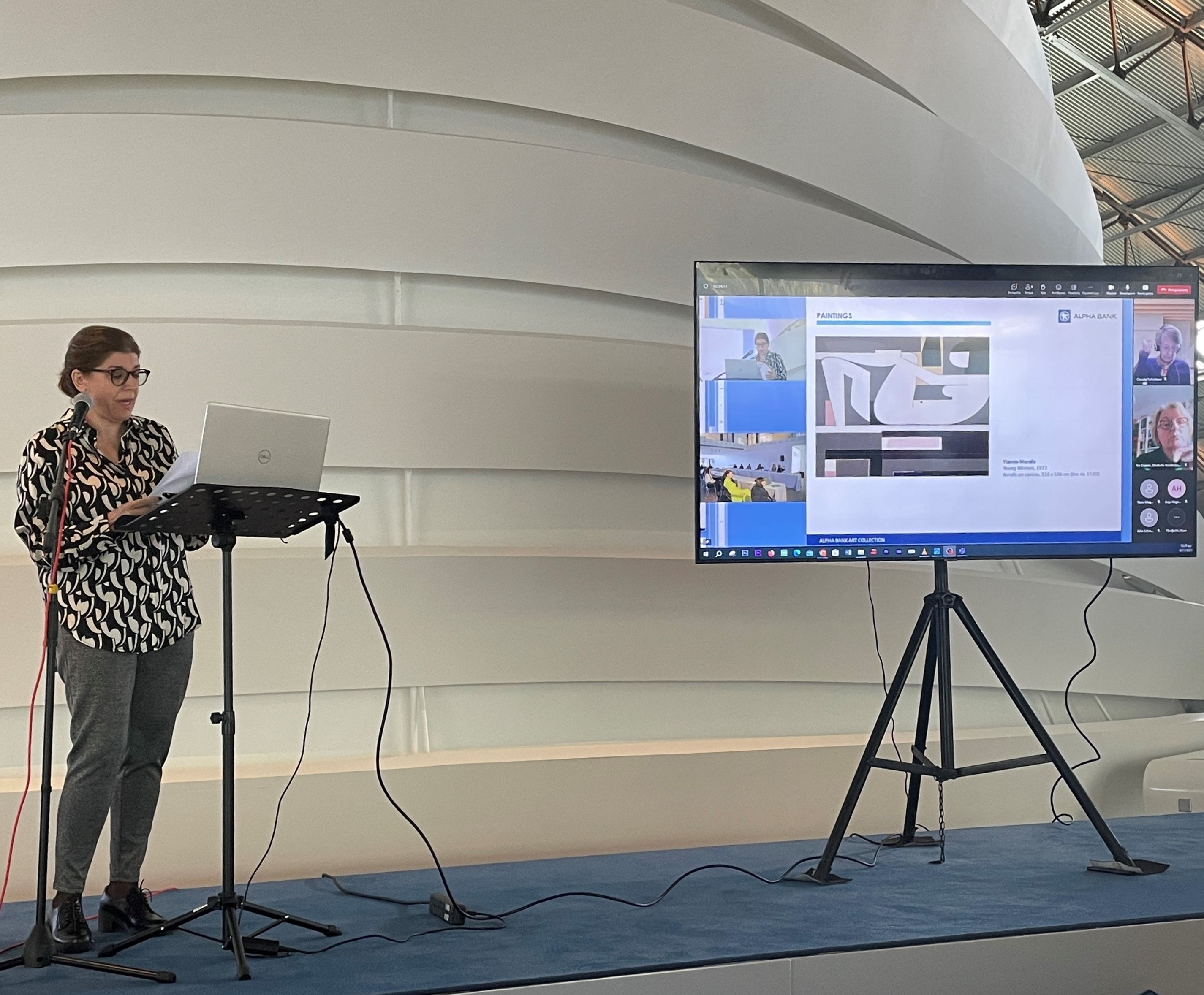 Στα αριστερά ομιλήτρια με μικρόφωνο και σημειώσεις και στα δεξιά οθόνη προβολής με τρίποδο. Συνάντηση μελών IACCCA στην Αθήνα