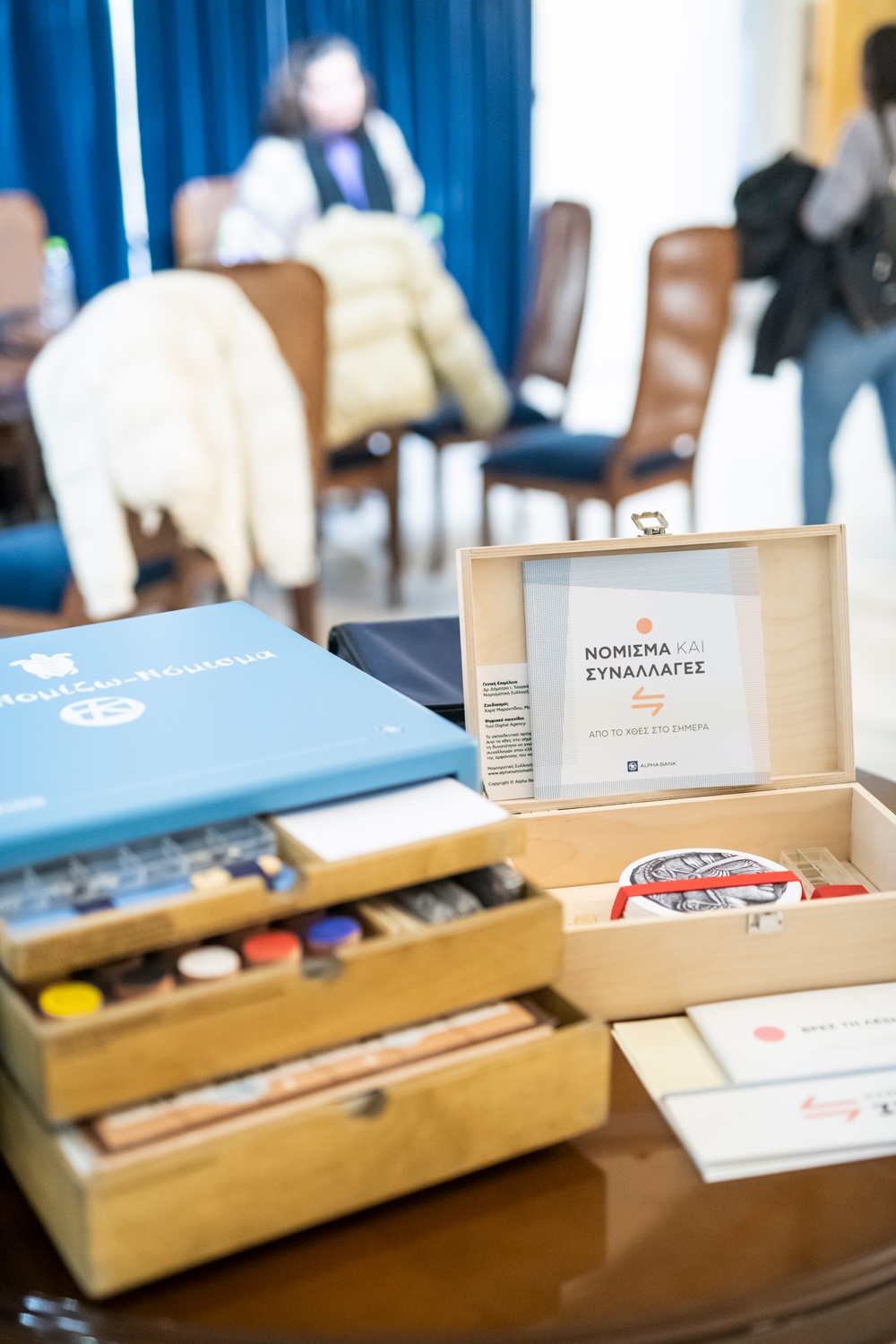 Οι 2 μουσειοβαλίτσες της Νομισματικής Συλλογής της Alpha Bank επάνω σε τραπέζι. Μουσειοβαλίτσες στο Κυριακοπούλειο Πολιτιστικό Κέντρο Ιτέας