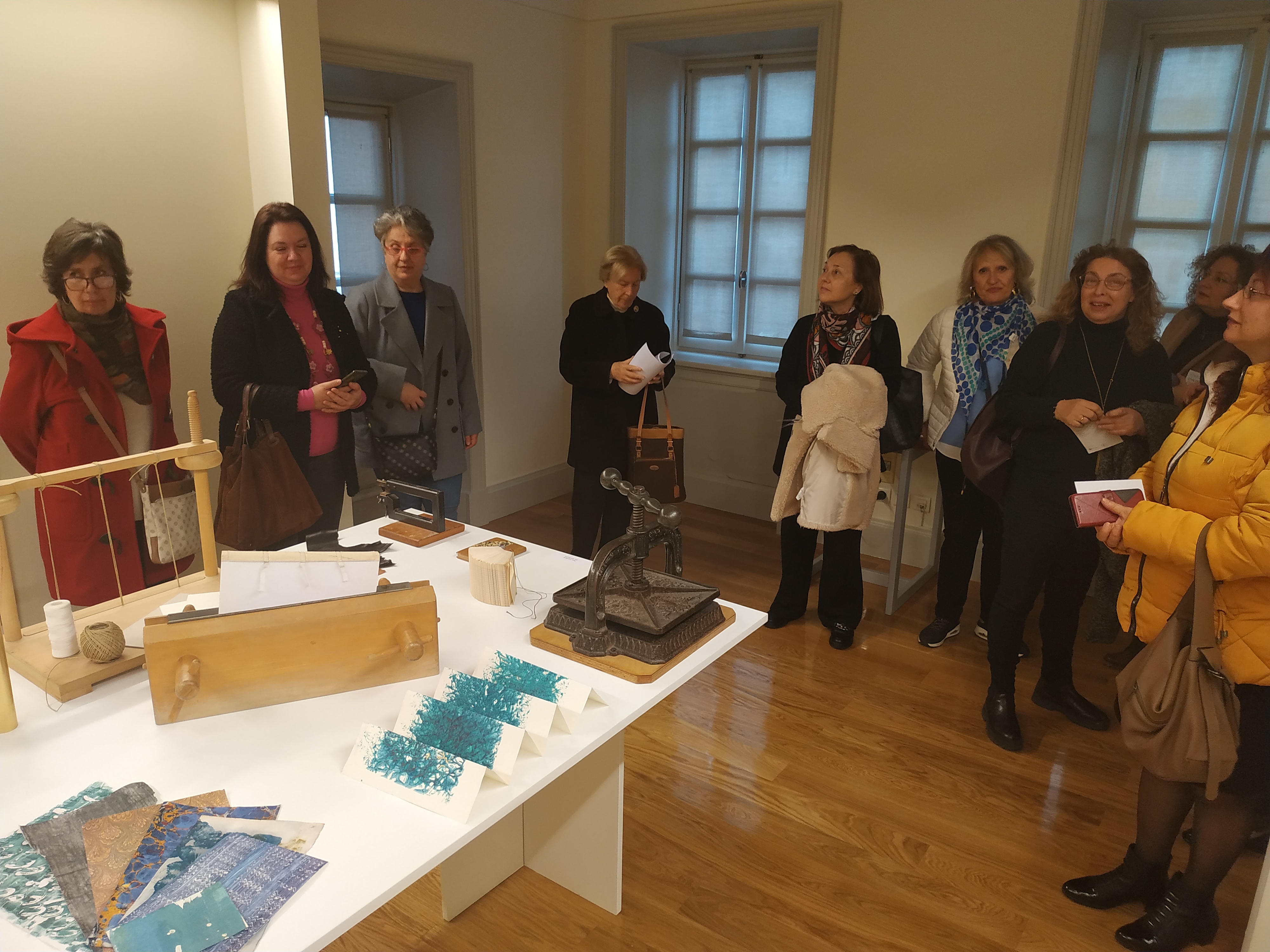 Women-members of the Corfu Soroptimist Club observing the tour next to a table with works by Evangelia Biza. Highlight from the visit