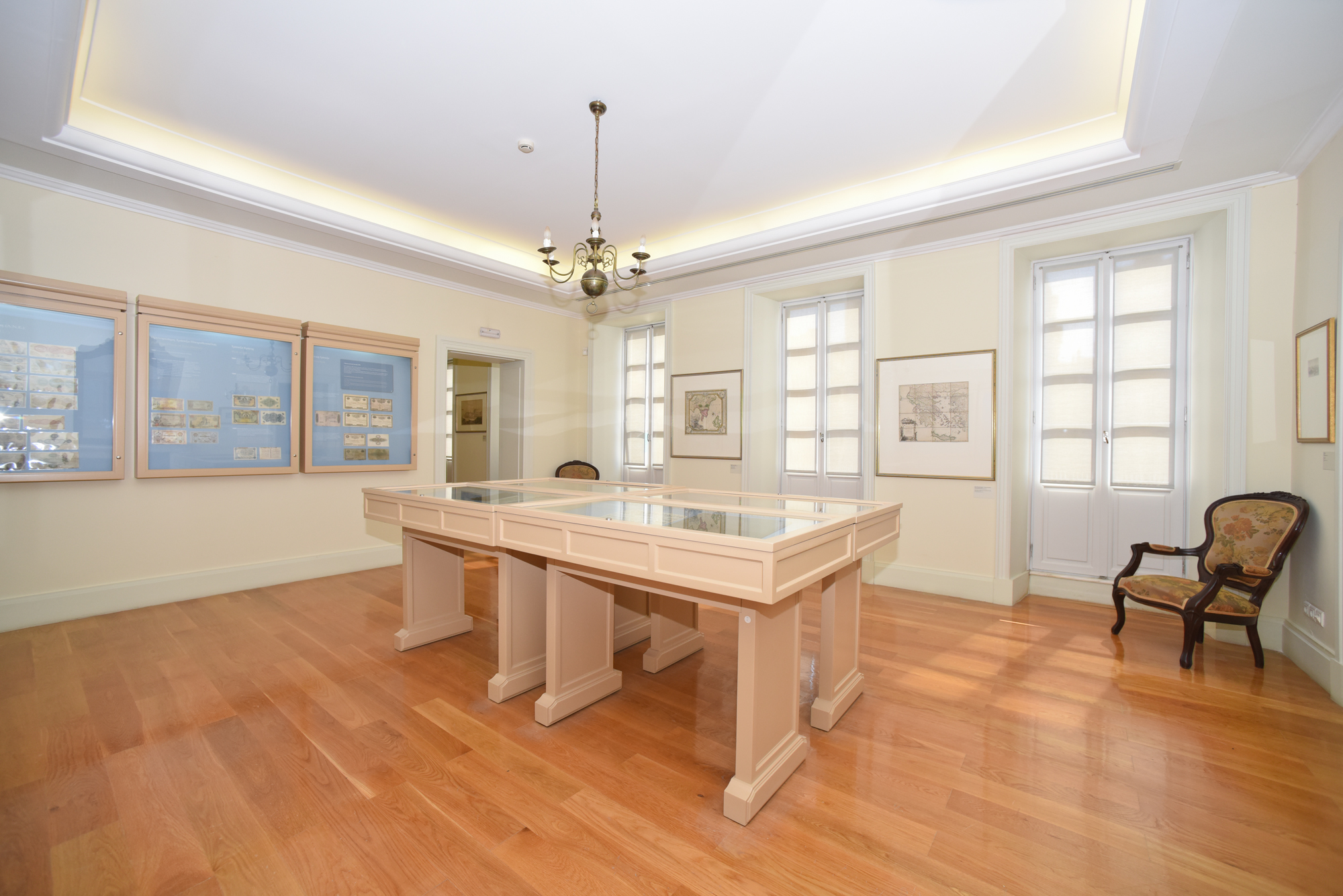 Αίθουσα του Μουσείου Χαρτονομισμάτων Ιονικής Τραπέζης με χάρτες και προθήκες με νομίσματα. 