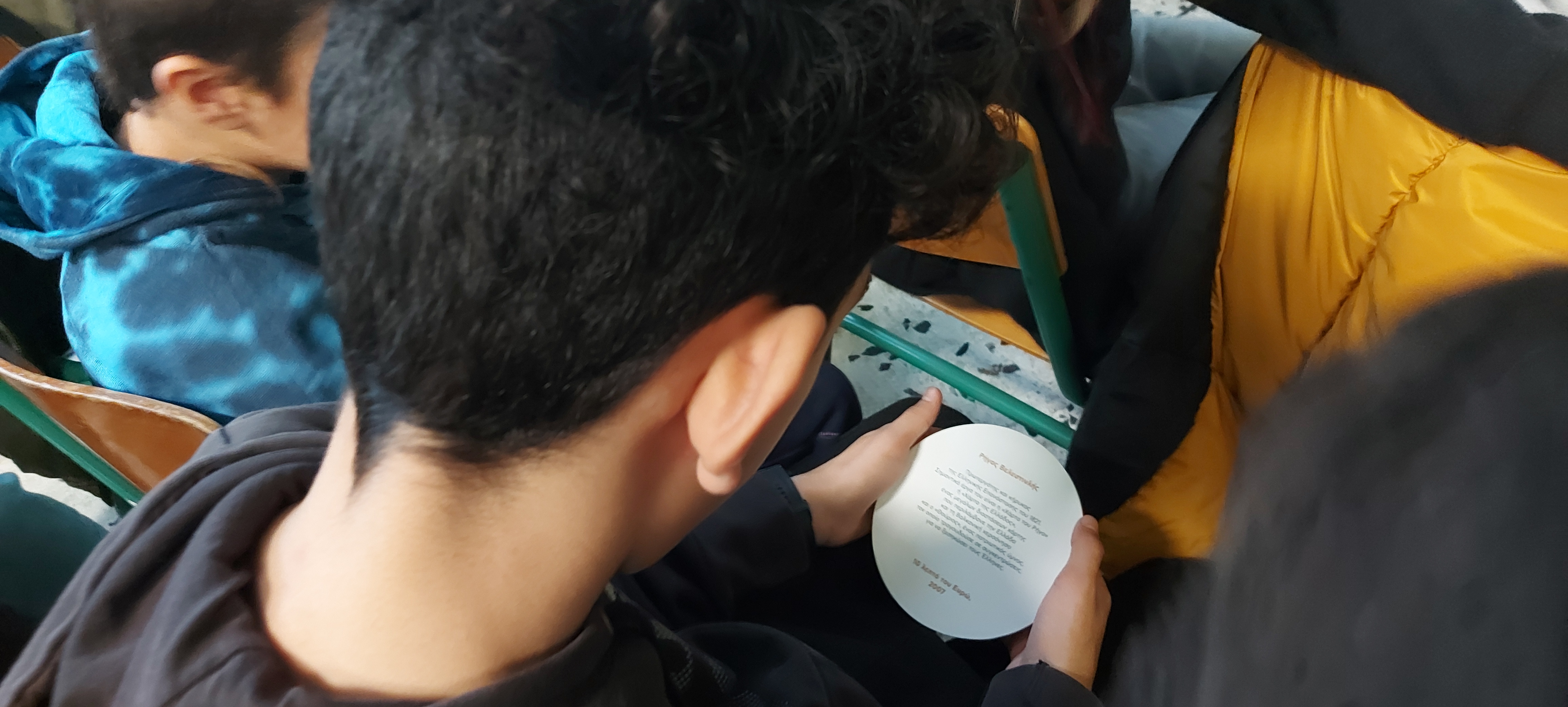 Αγόρι διαβάζει για τον Ρήγα Βελεστινλή στην πίσω όψη χάρτινης απομίμησης ενός νομίσματος των 10 λεπτών. Εκπαιδευτικό υλικό