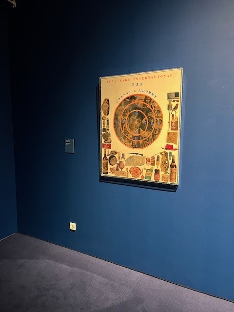 The piece Skopovoli by Chryssa Romanos hanging on a dark blue wall. The piece at the exhibition area