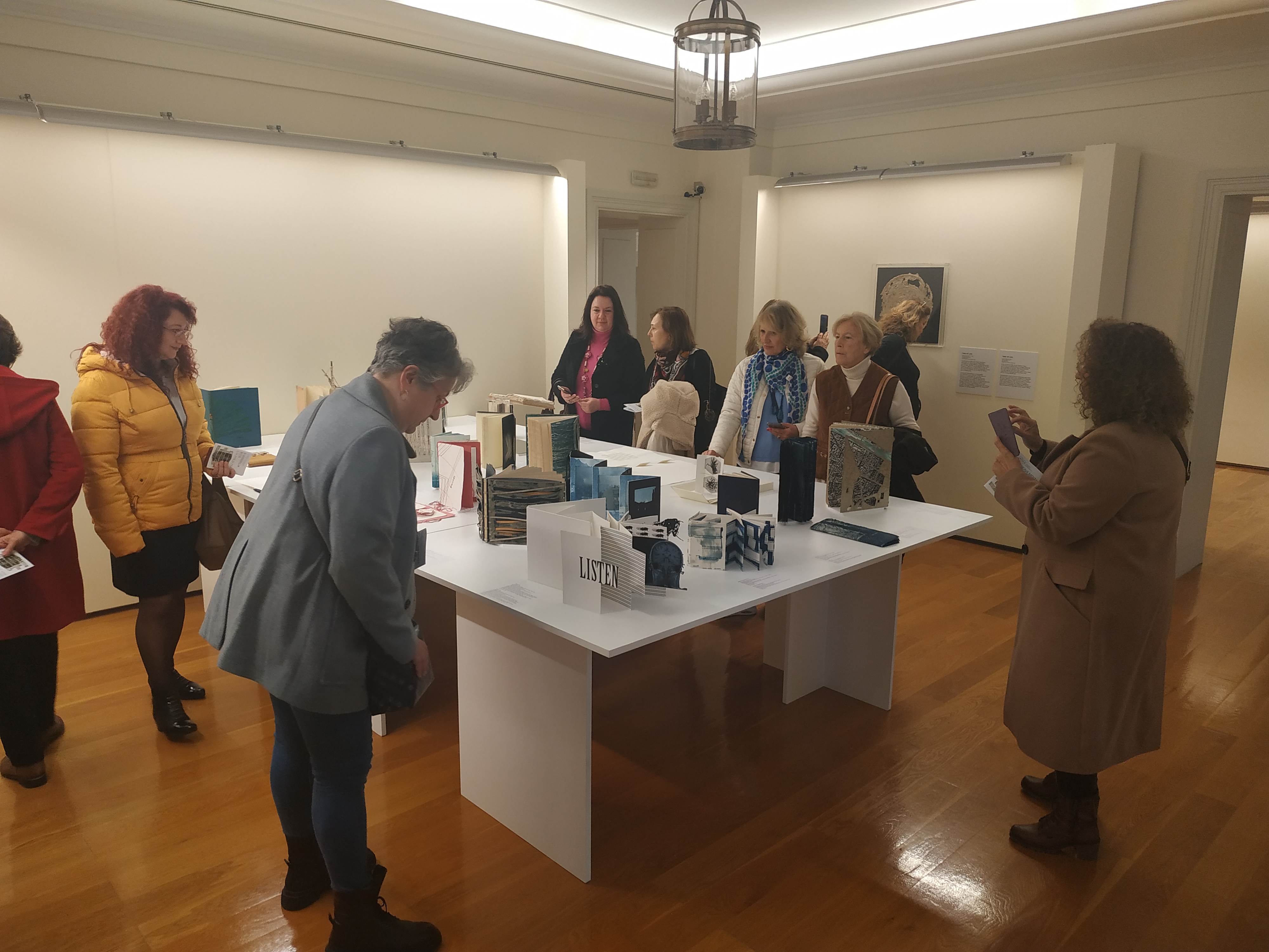 Women-members of the Corfu Soroptimist Club around a table with works by Evangelia Biza. Highlight from the visit